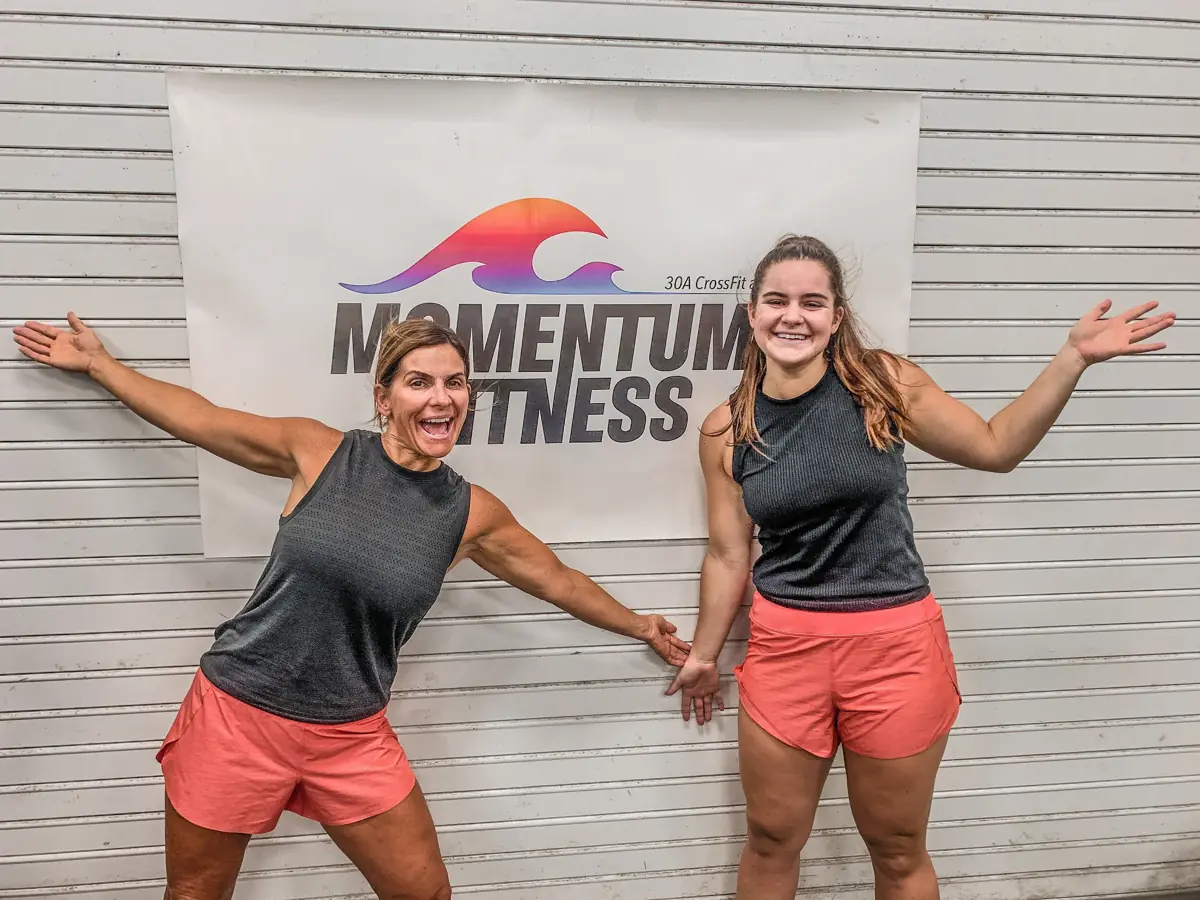 Two members striking a pose in front of the Momentum banner