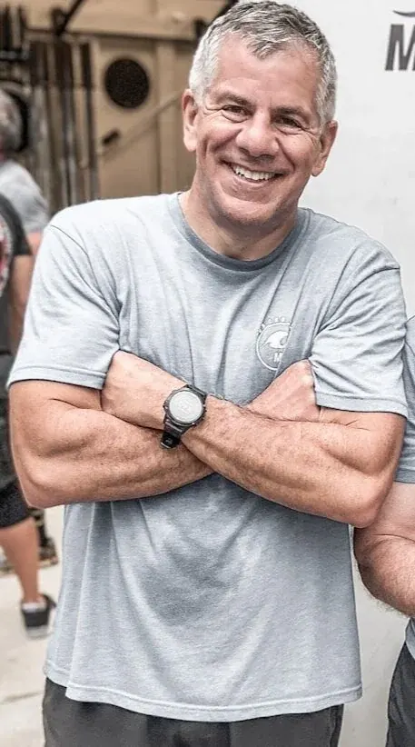John with his arms crossed, smiling, in the gym