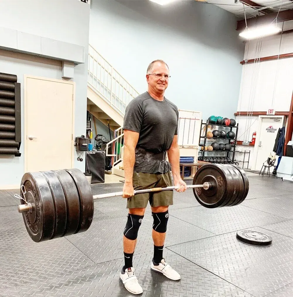 A member standing tall with a heavy deadlift